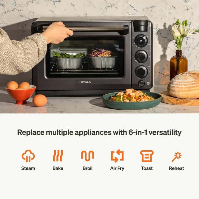 Person placing food in a multifunctional Tovala oven, surrounded by ingredients; text promotes its 6-in-1 versatility: steam, bake, broil, air fry, toast, reheat