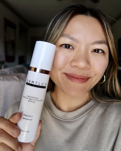 reviewer selfie wearing tinted moisturizer, holding bottle