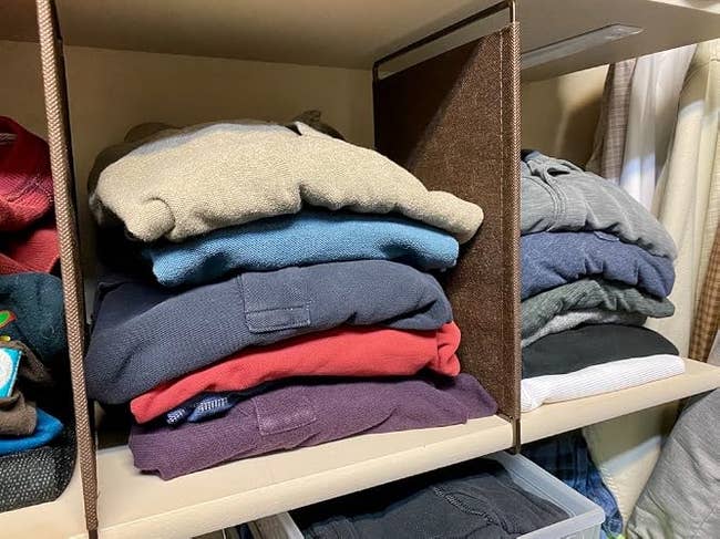 Stacked sweaters connected  closet shelves, organized by colour  and neatly folded, suggest   a cozy and stylish wardrobe for colder seasons
