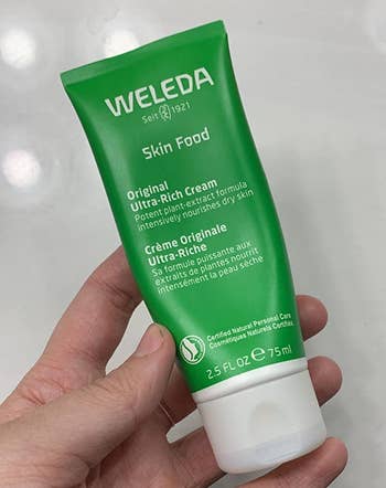 reviewer holding the green tube of skin cream