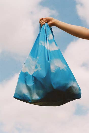 A reviewer holding a reusable tote bag with a cloud print 
