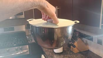 Hand lifting a stainless alloy  mixing vessel  with a lid successful  a modern   room  setting