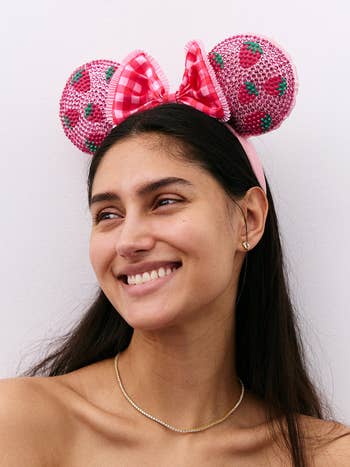 Person smiling, wearing a headband with embellished rodent ears and a checkered bow