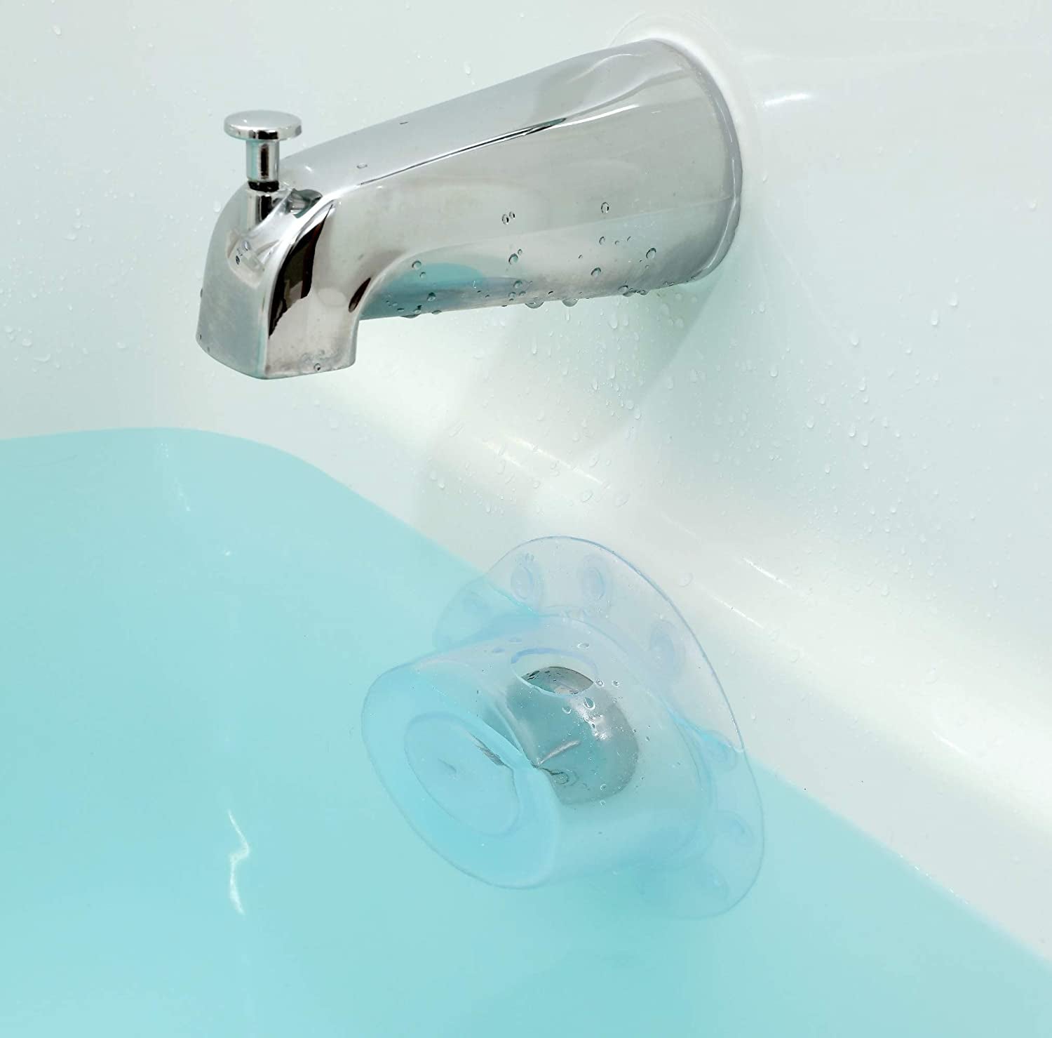 the clear drain cover over the drain of a full bathtub