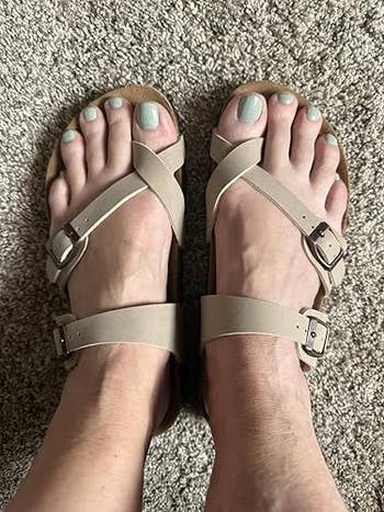 Person wearing strappy sandals with adjustable buckles connected  some  feet, lasting  connected  a carpeted floor