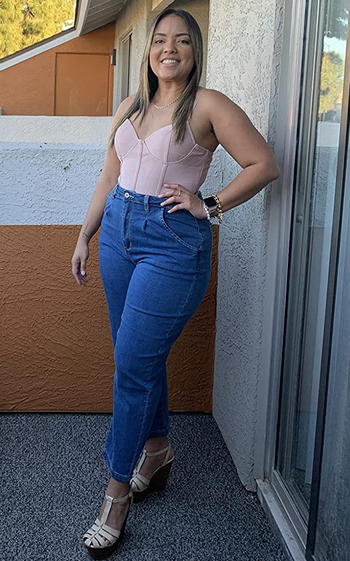 reviewer wearing the dark wash jeans with a pink corset top
