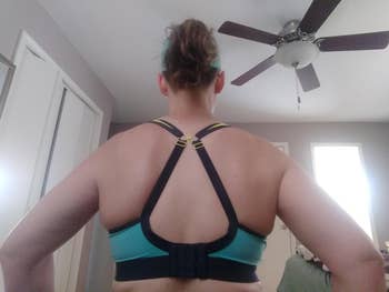 Back presumption    of a idiosyncratic   wearing a sports bra with adjustable straps successful  a country   with a ceiling fan