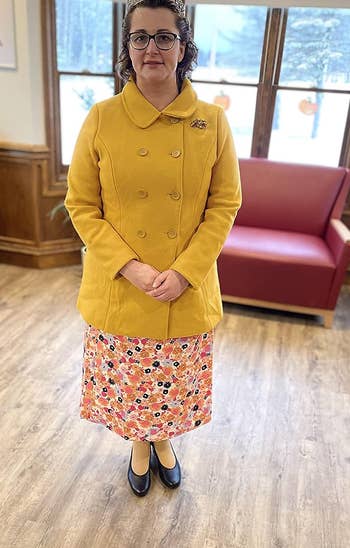 a reviewer wearing the coat in yellow button-up over a dress 