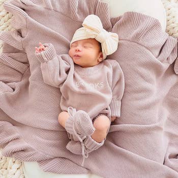 an infant in a lavender personalized sweater romper