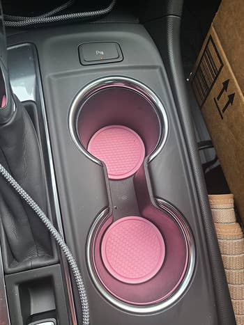 reviewer photo of their car's console with pink coasters in two cup holders