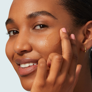 a model applying the sunscreen on their cheek 