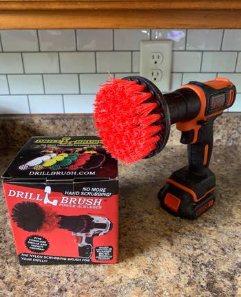 a reviewer photo of a red scrub brush mounted on a drill 