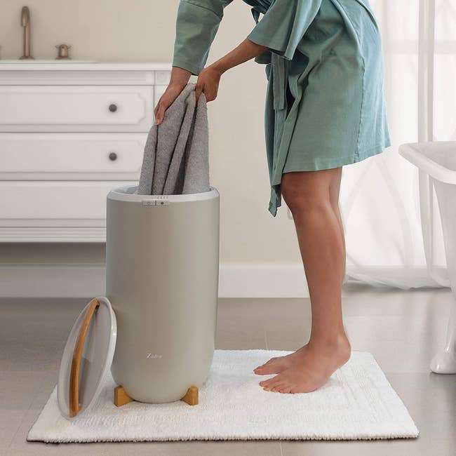 model grabbing towel from the circular-shaped gray bin