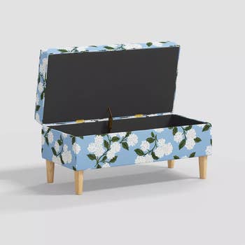 a storage bench in a light blue color with white hydrangeas on it
