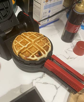 a reviewer's waffle maker with a waffle cooking in it 