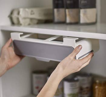 Model pulling a horizontally stored spice storage attachment from the bottom of a cabinet 