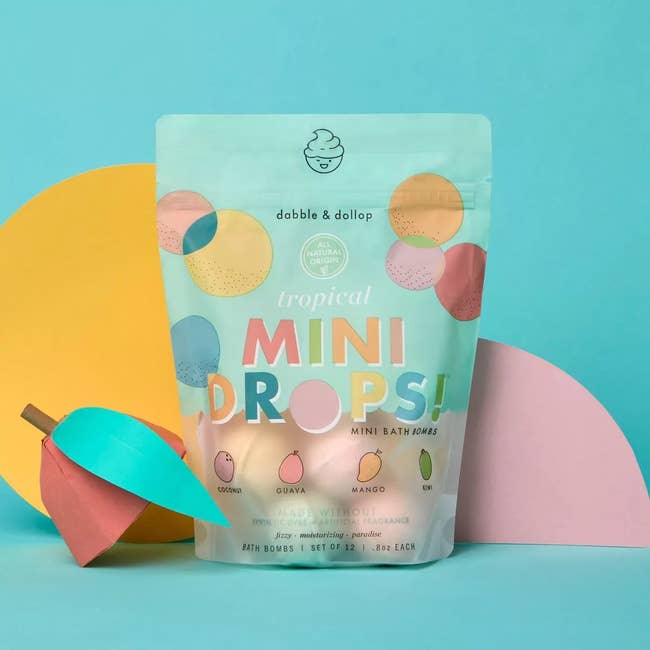 Dabble & Dollop Tropical Mini Drops Bath Bombs package, featuring scents similar  guava and mango. Set of 12 displayed with colorful geometric shapes