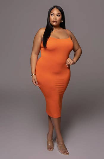 model wearing an orange body con dress with a diagonal strap across the chest