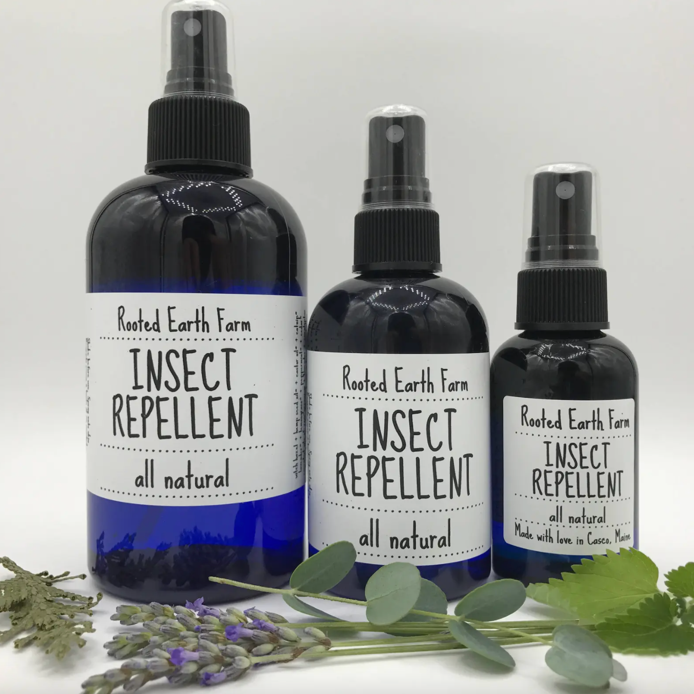 three bottles of insect repellant next to lavender
