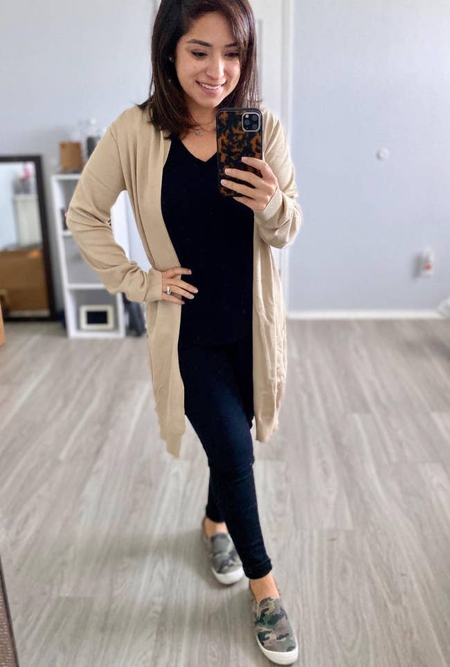 reviewer wearing the mid-thigh length cardigan in tan