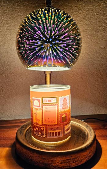 Decorative lamp with a glowing, dotted sphere connected  apical  of a candleholder featuring gift-themed designs