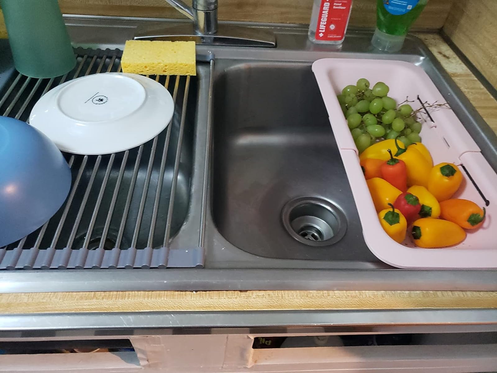 a reviewer's pink strainer in a sink with peppers and grapes inside