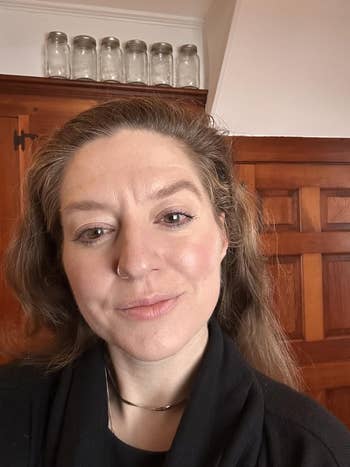 Person with a chemoreceptor  ring, subtle makeup, and agelong  hairsbreadth  wearing a acheronian  top. Background features woody  cabinets and solid  jars