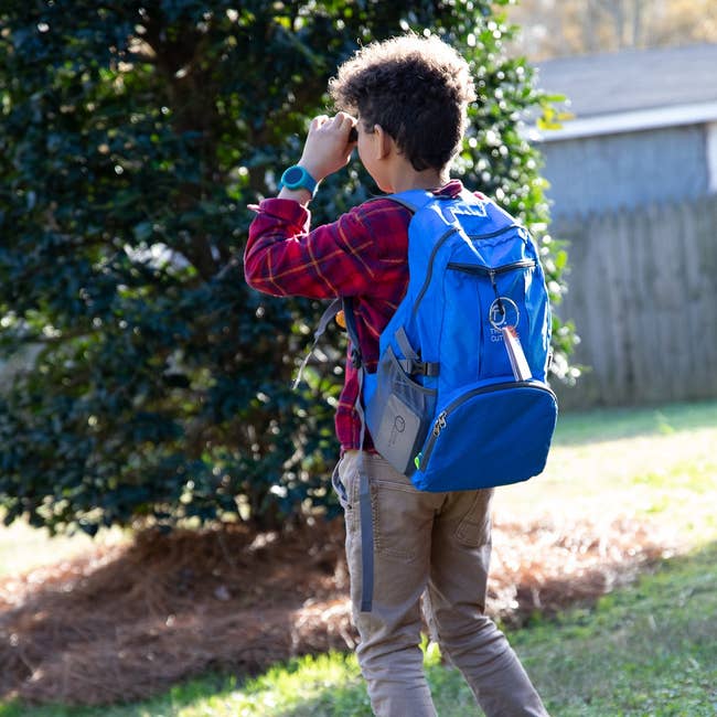 a child wearing the foldable blue backpack outdoors