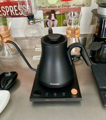 Electric gooseneck kettle on a kitchen counter with coffee-making equipment in the background