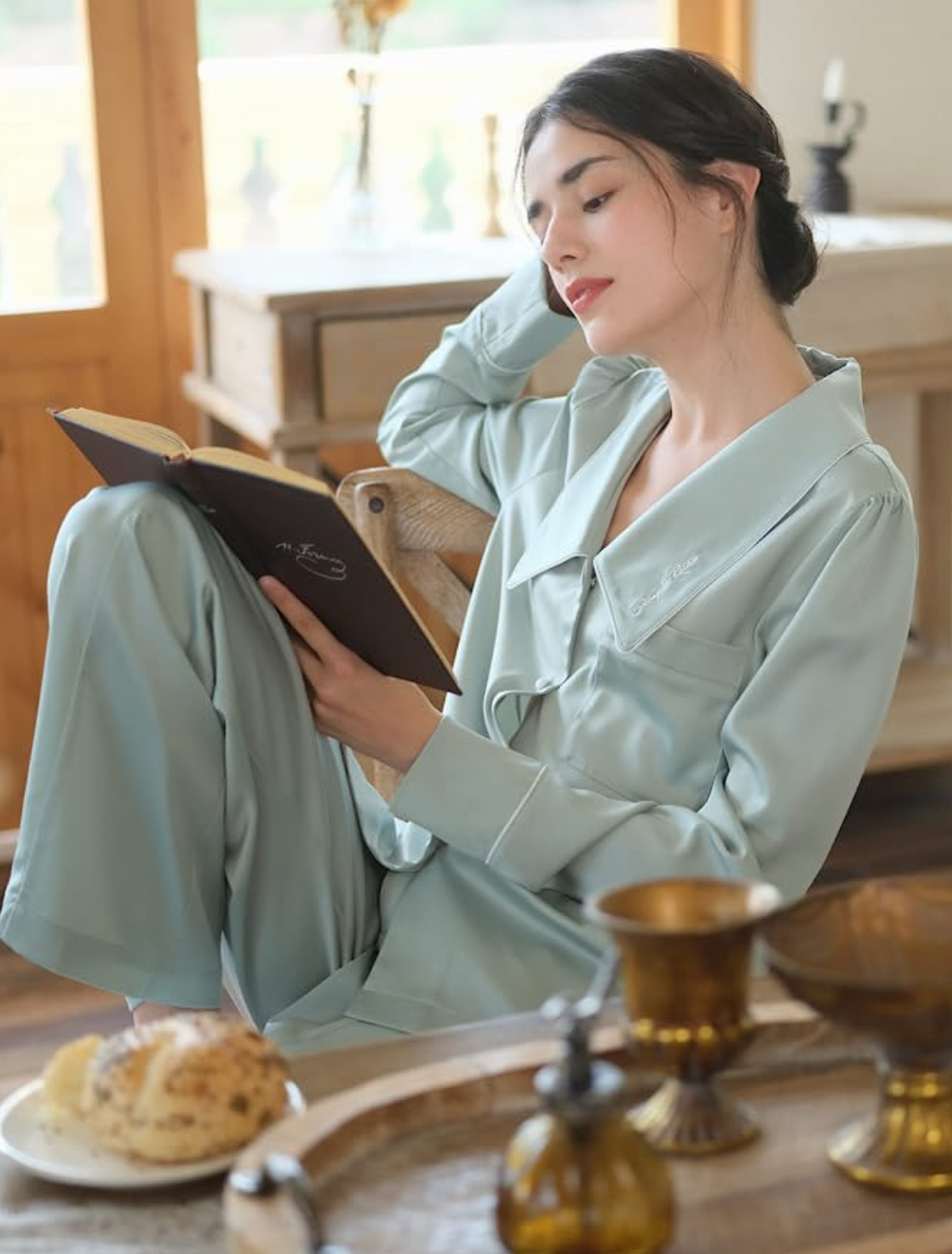 a model wearing the pajama set while eating breakfast and reading