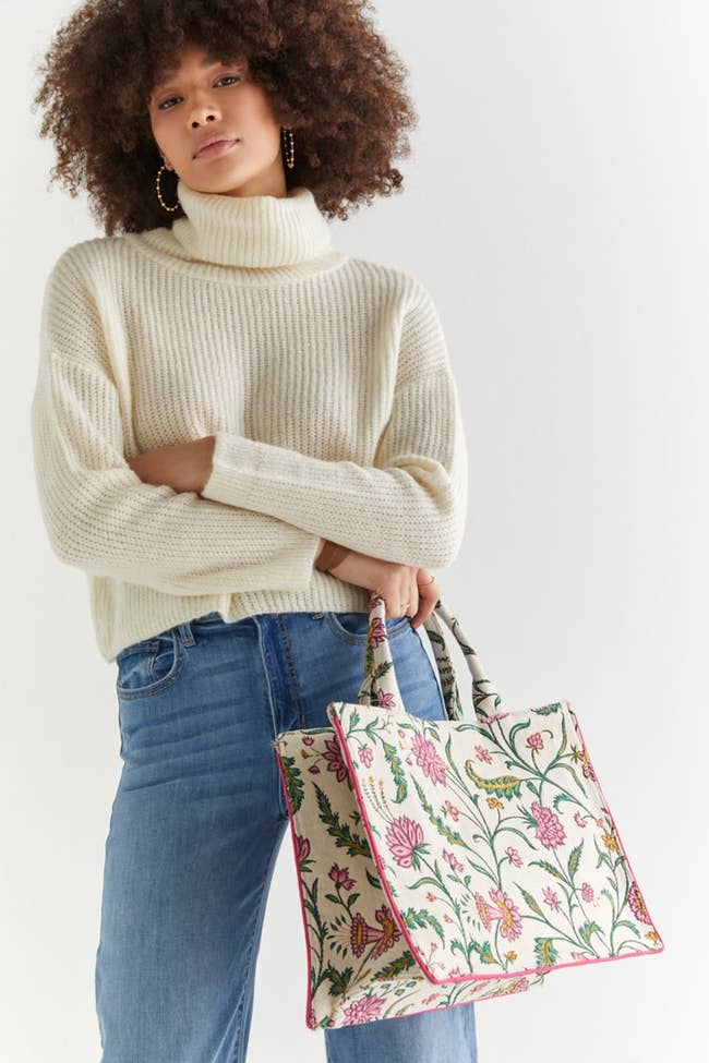 model carrying cream rectangular tote with pink and green floral print