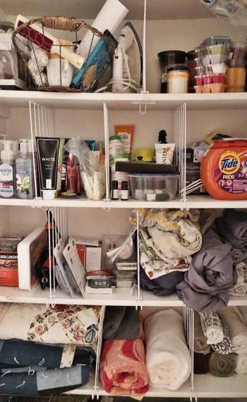 The closet dividers organizing a shelf of blankets and laundry soap