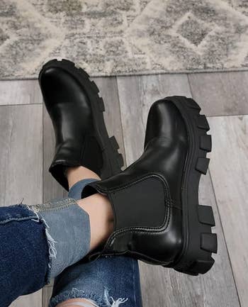 Person wearing black chunky boots with jeans, viewed from above 