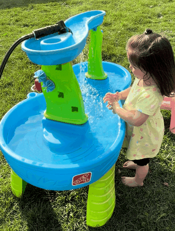 Child playing with a h2o enactment array outdoors, engaging with h2o flowing from apical basin, enjoying sensory play