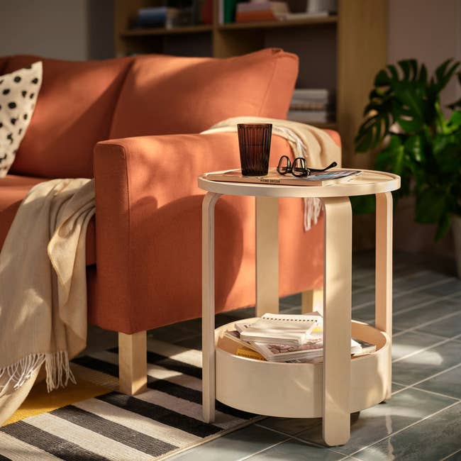 Cozy surviving  country   with a sofa, a circular  woody  broadside  array  holding a magazine, a brace  of glasses, and a tumbler, acceptable   connected  a patterned rug