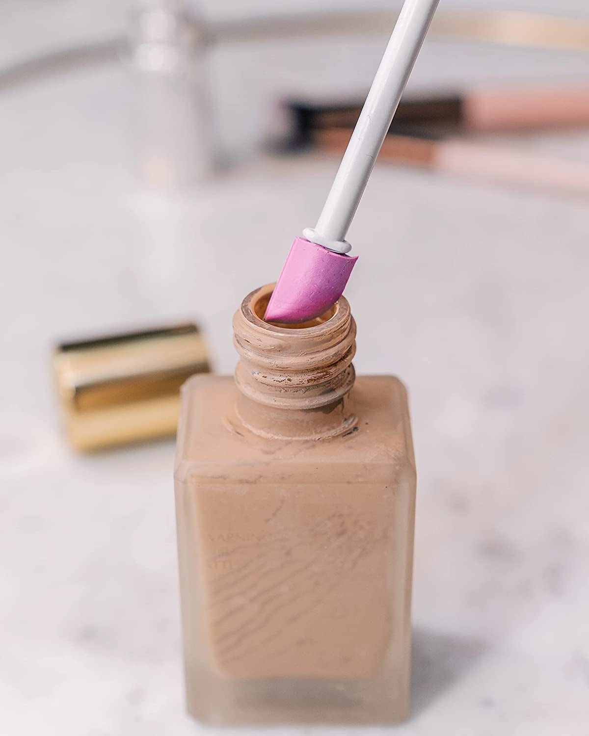 the Spatty scooping up leftover foundation from the bottom of a jar