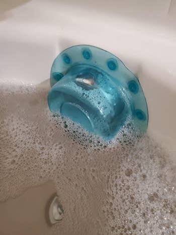 reviewer photo of the blue overflow drain cover keeping water in a tub from draining out