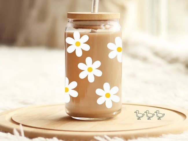 a glass can with daisies on it