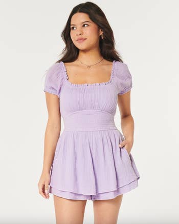 Model in a short-sleeved, square neckline, smocked lavender skirted romper 