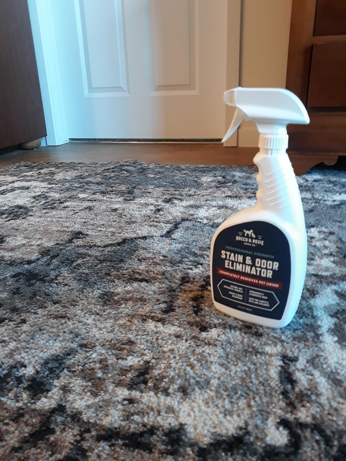 Spray bottle of Rocco & Roxie Supply Co. Stain & Odor Eliminator on a freshly clean carpeted floor