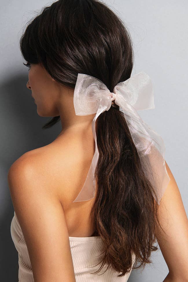 a model wearing a light pink organza bow in their hair