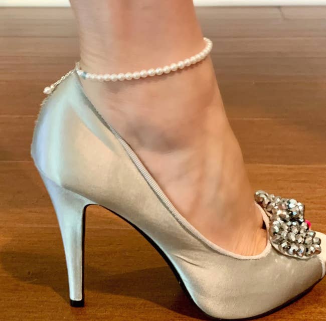 The pearl anklet with a tiny blue crystal worn around the model's ankle