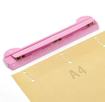 pink 3 hole punch next to paper