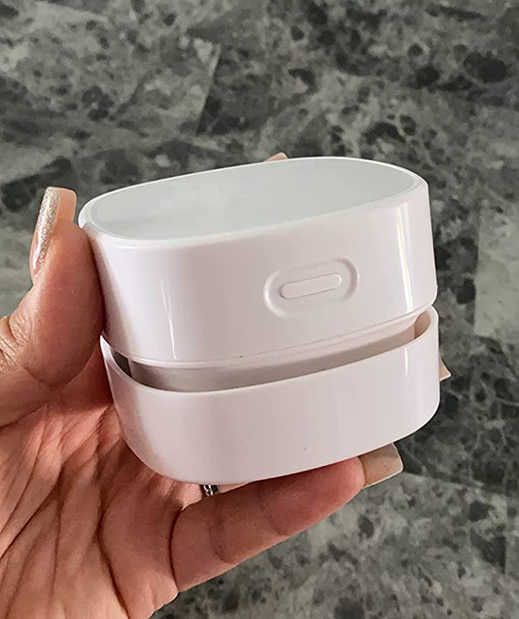 Reviewer holding their sleek white mini vacuum