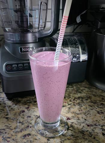 a reviewer photo of a purple smoothie made in the ninja 