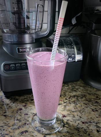 a reviewer photo of a purple smoothie made in the ninja 