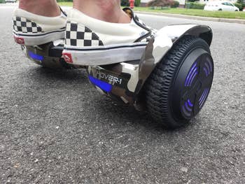 Close up of reviewer on the camo hoverboard with blue lights