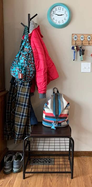 Reviewer image of the black coat rack with shoe storage and coats and a bag on top