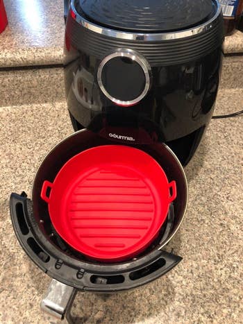 Reviewer's top-down view of the red silicone basket in an air fryer