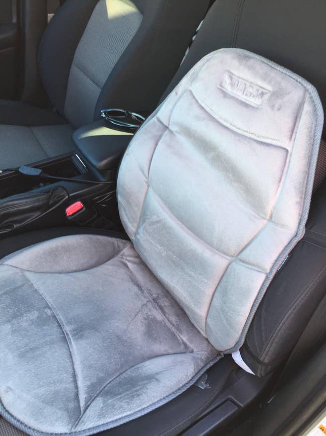 reviewer image of the grey heated car cushion on the driver's seat of a car